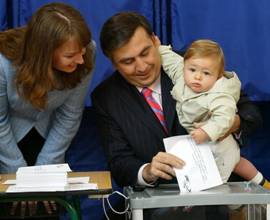 Georgian President Mikhail Saakashvili casts his ballot as he holds his son Nikoloz and first lady Sandra Roelofs (L) looks at them during local elections in Tbilisi, 05 October 2006. Local self-rule elections began in Georgia on Thursday.  According the Central Election Commission, 3,033 polling stations were opened, including four in the upper Kodori Gorge that Georgian authorities call Upper Abkhazia. AFP PHOTO / VANO SHLAMOV

(Photo credit should read VANO SHLAMOV/AFP/Getty Images) From Getty Images by AFP/Getty Images.